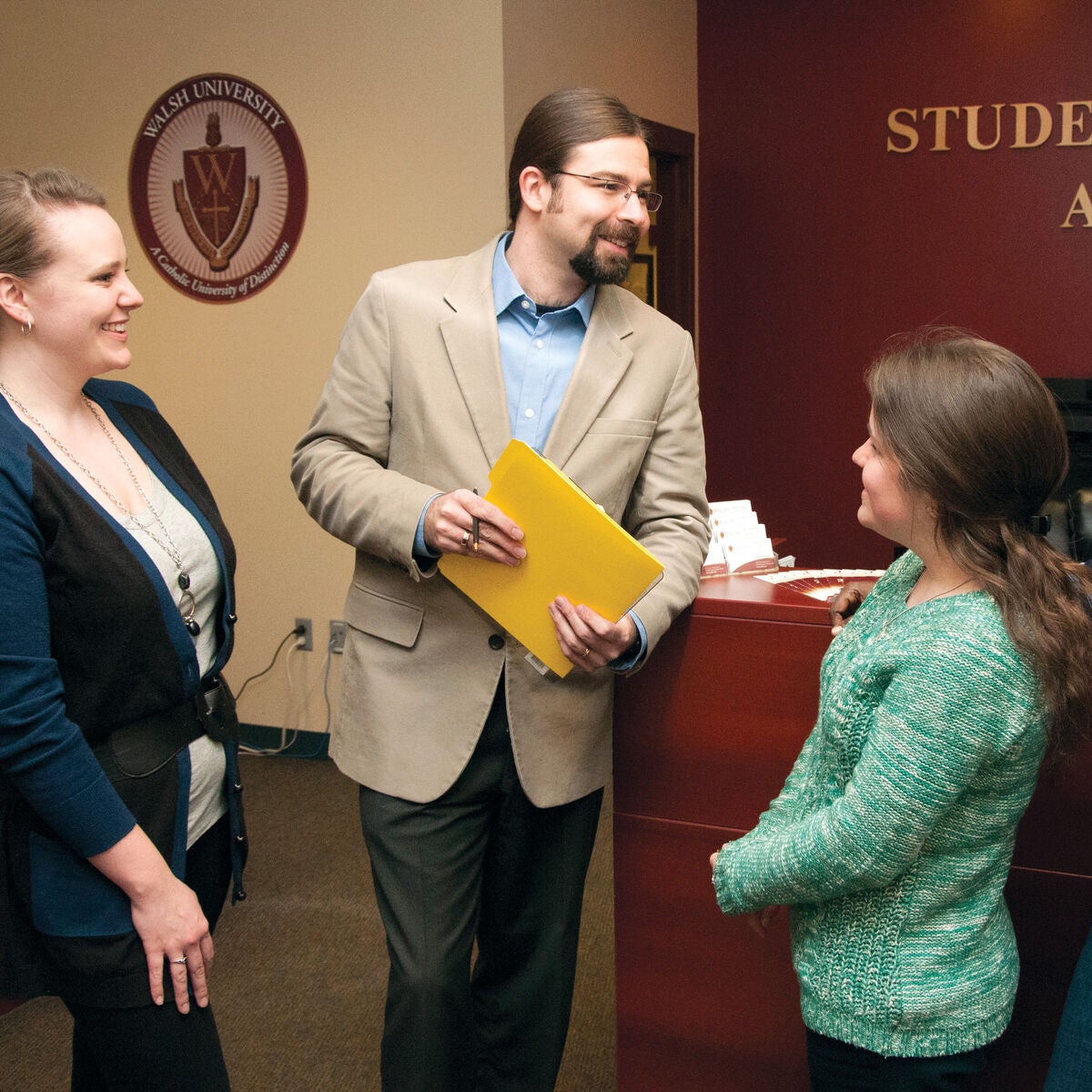 Walsh Student advisor is holding a file and talking to students
