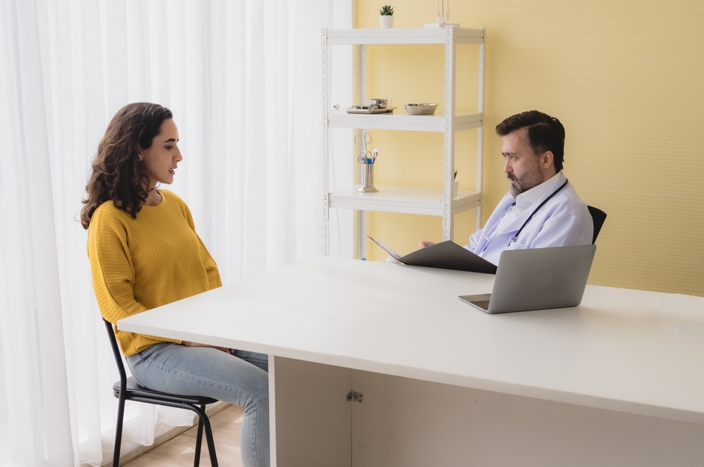 A psychiatric mental health nurse sits and talks with a patient.