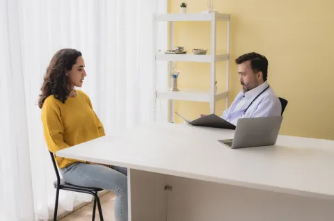 A psychiatric mental health nurse sits and talks with a patient.